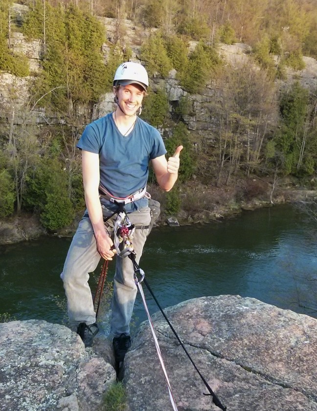 Tyler leans back and is ready to repel down the rock face