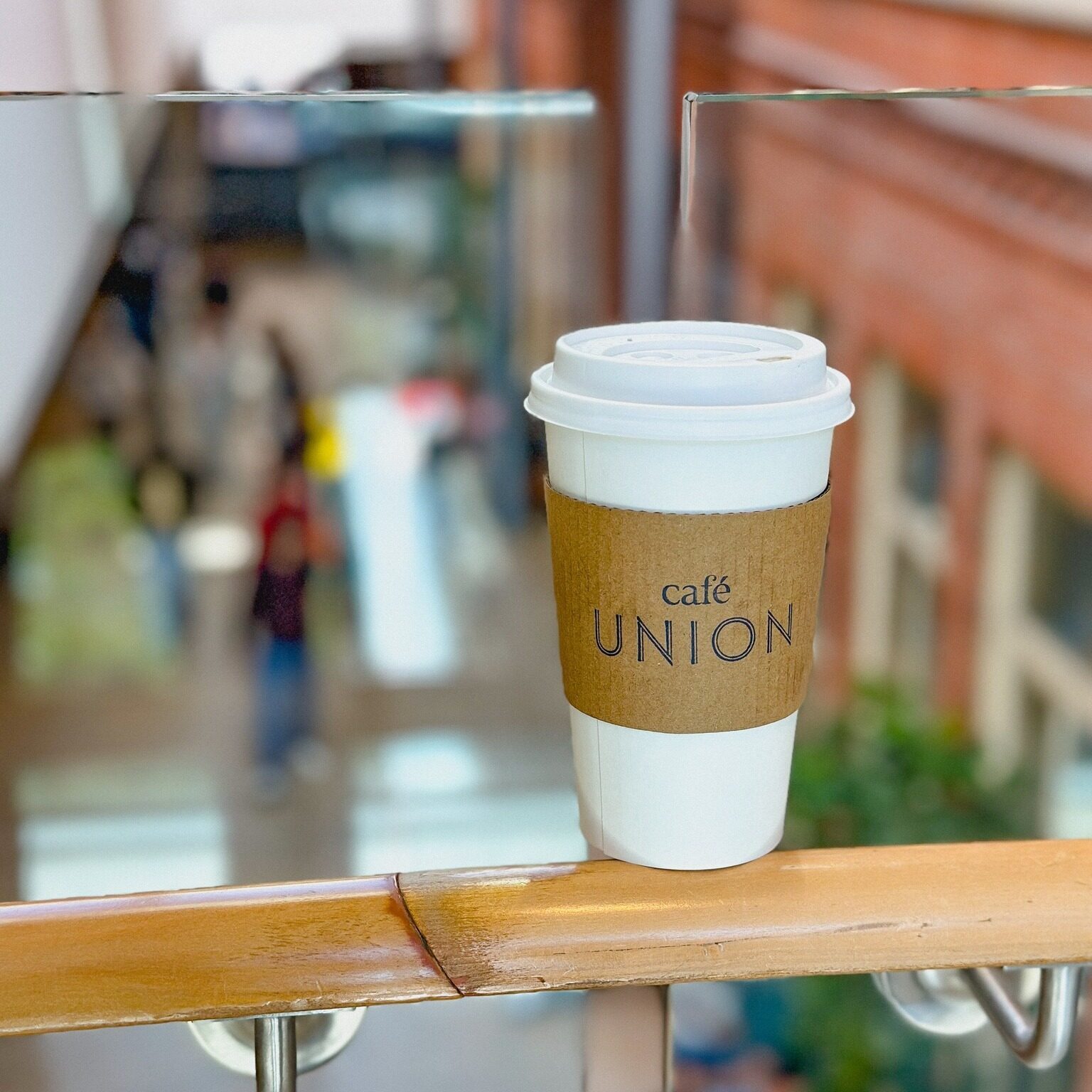 Cafe Union to-go cup placed on a handrail overlooking a lower floor.
