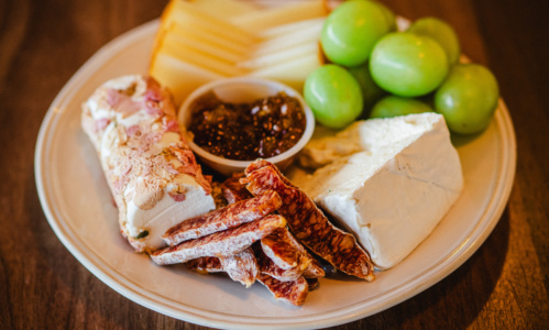 A plate of cheese, fruits and meats from Flight Cheese Shop.