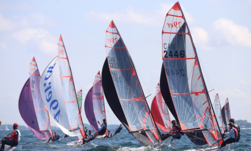 A group of people sailing on the waters of Kingston under a clear blue sky.