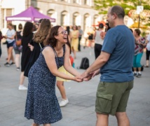 Two people holding hands, laughing, and dancing salsa at Market Square.