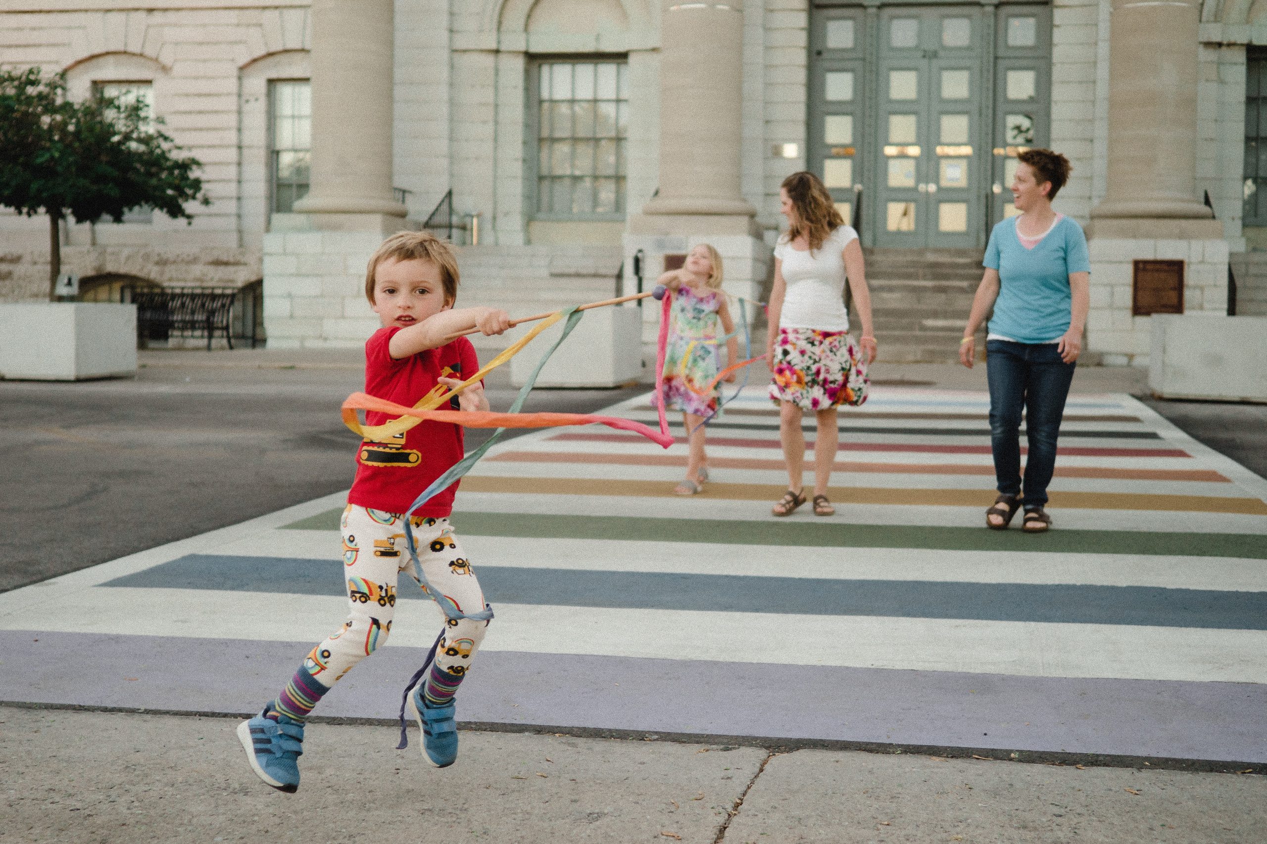 Kids walking across a rainbow crosswalk