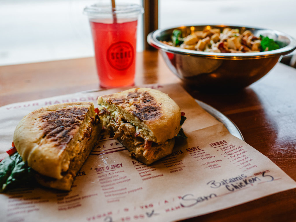 A balsamic chicken sandwich with salad and a drink from Score Pizza